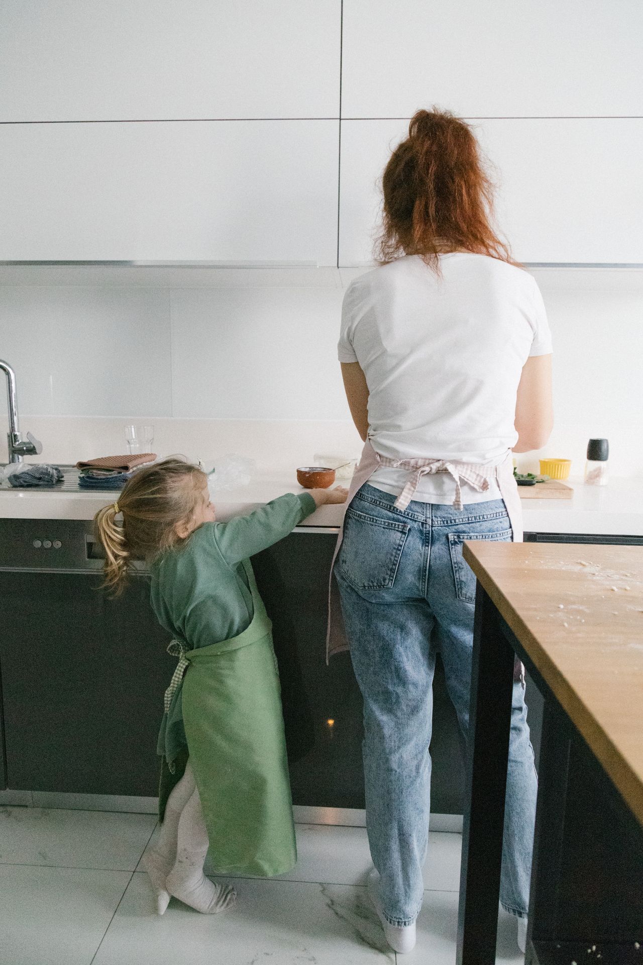 Young child helping a parent prepare a meal in a home kitchen