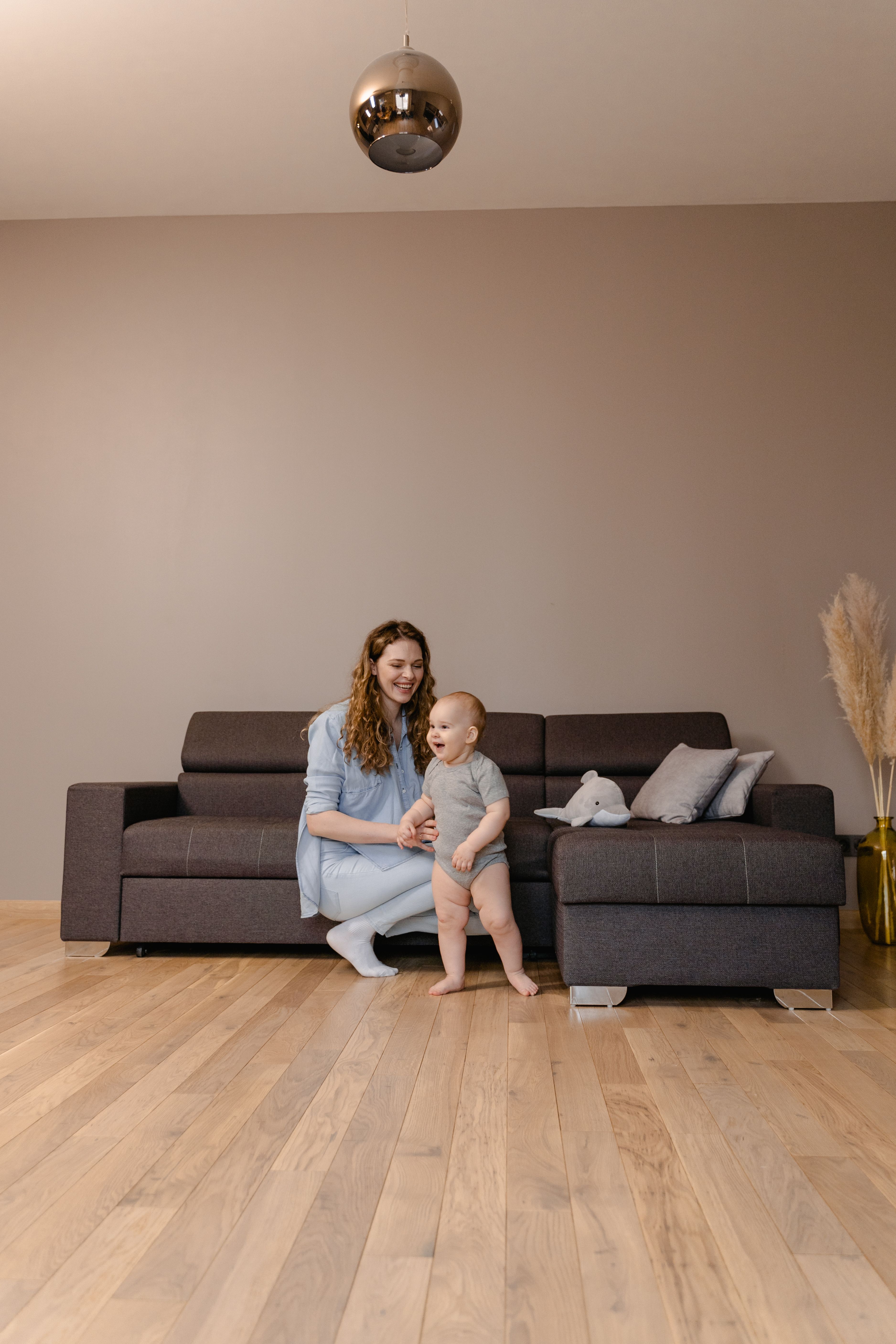 A parent playing with a young child on the floor of a bright living room at home