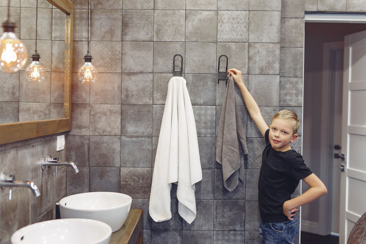 A young boy hanging towels in a bathroom - ABA Therapy