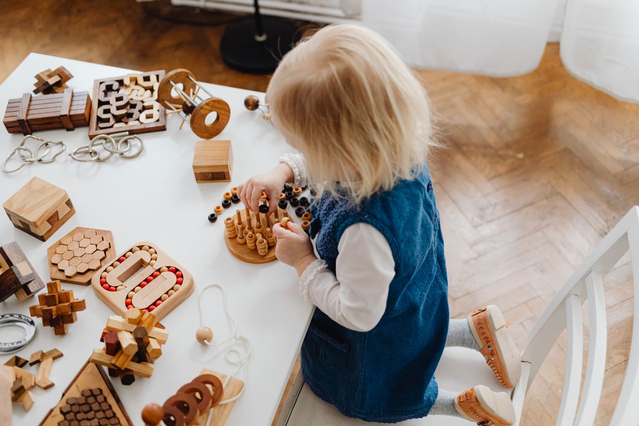 A young child playing with wooden toys at a table during a play-based speech therapy session